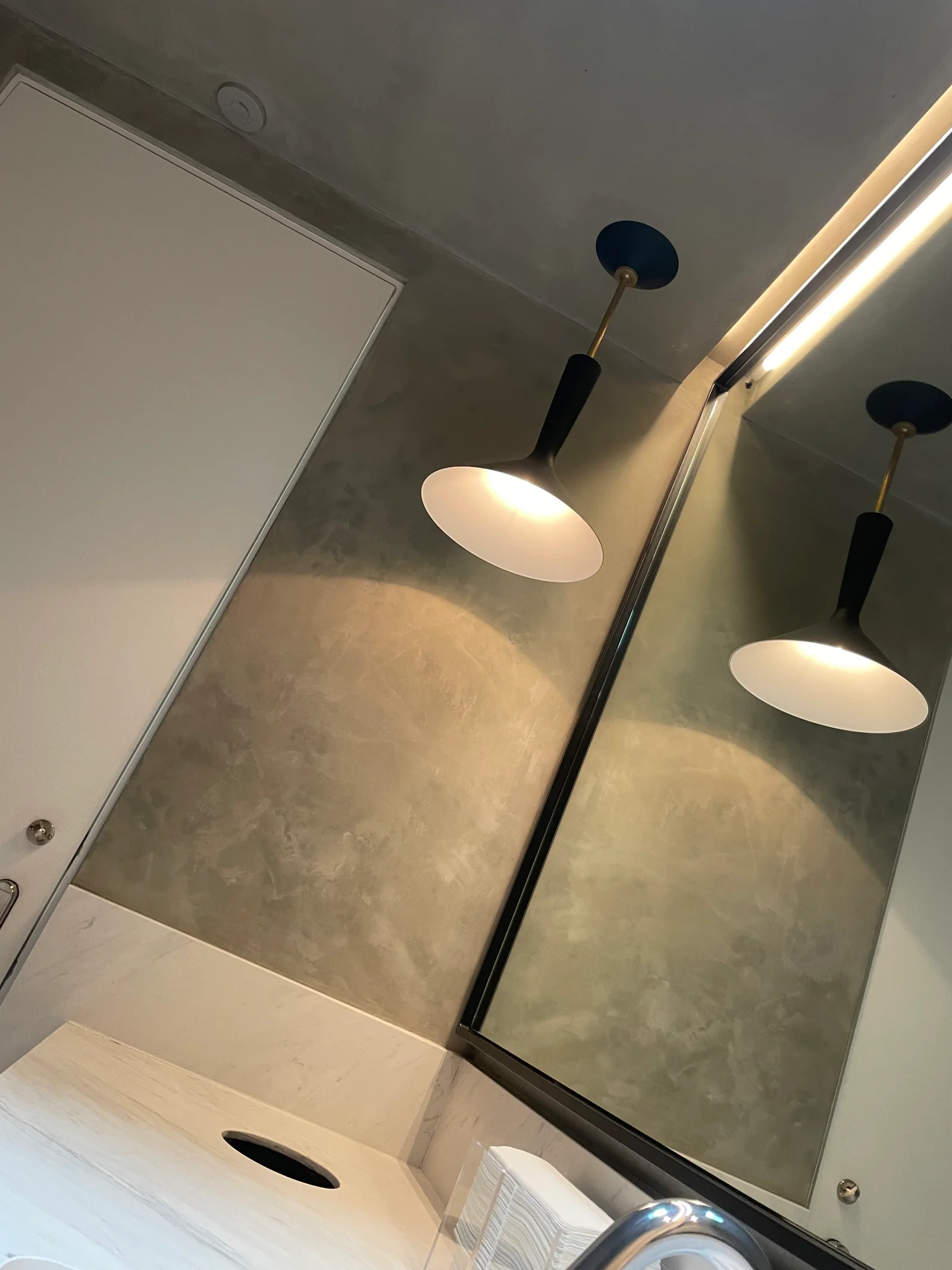Polished concrete bathroom walls with black pendant lights and white trim