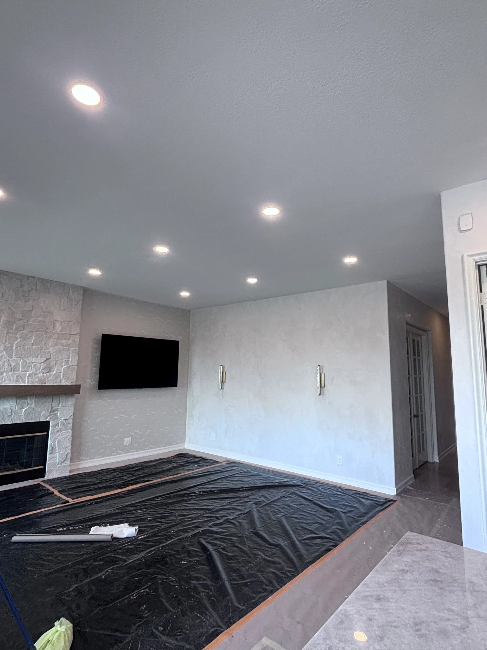 Finished drywall walls with recessed ceiling lights and textured fireplace accent in residential room
