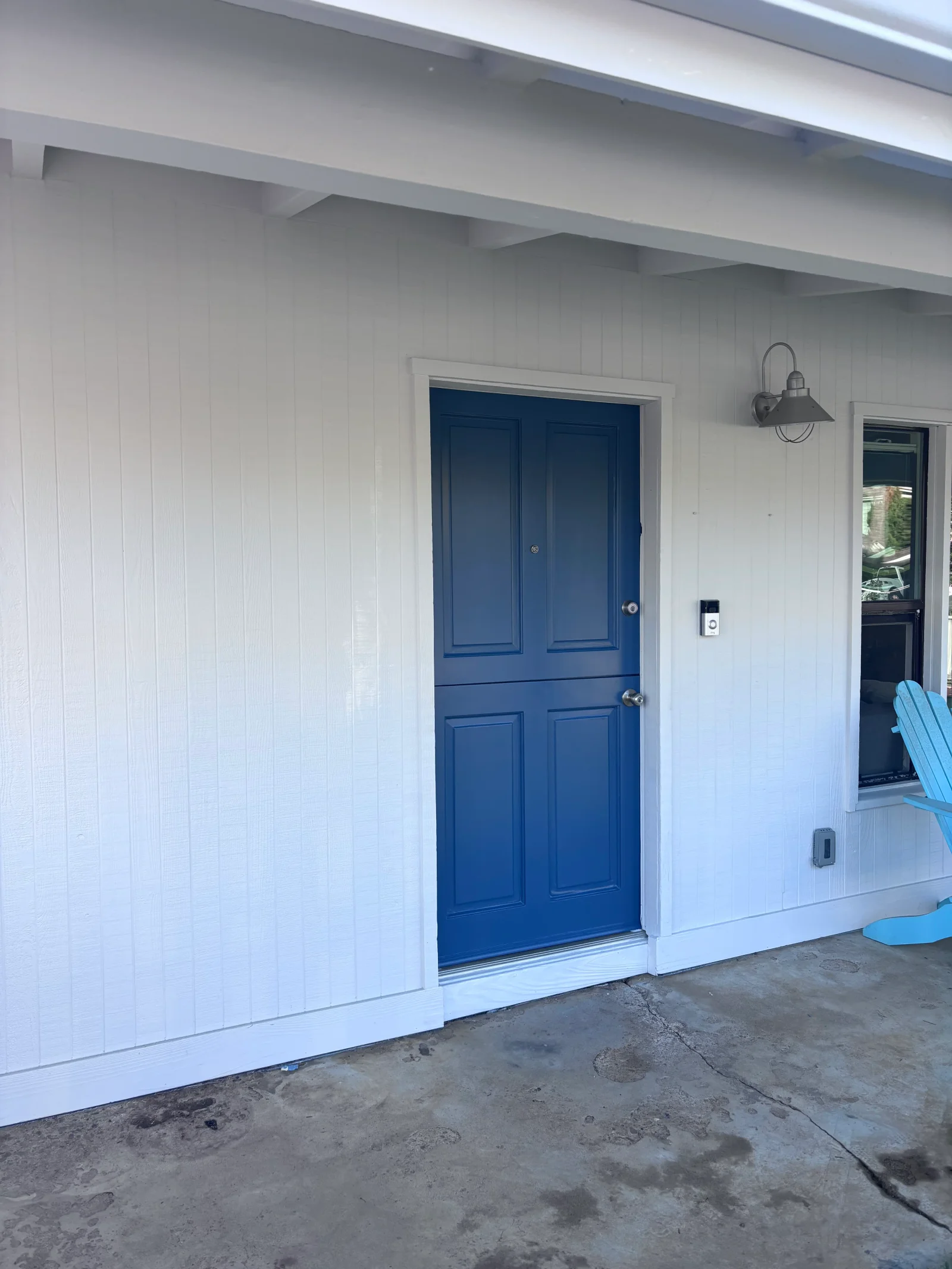 White painted garage exterior with navy blue six-panel door, exposed beam ceiling, and new lighting fixture
