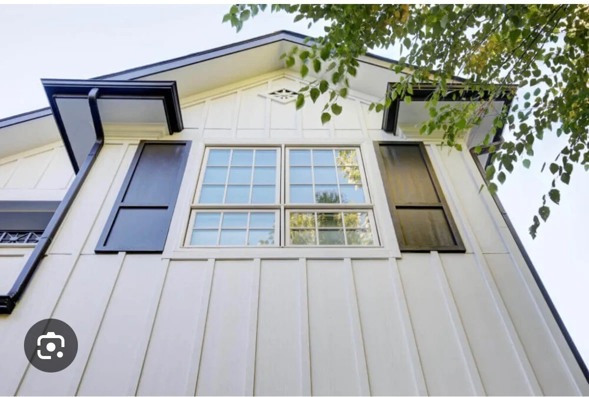 White vertical siding with navy trim, multi-pane windows, and dark shutters on modern home exterior
