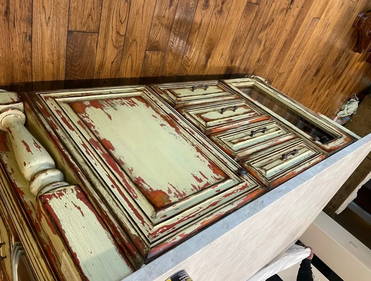 Distressed cream and red painted cabinet doors with layered finish and aged patina on wooden work surface