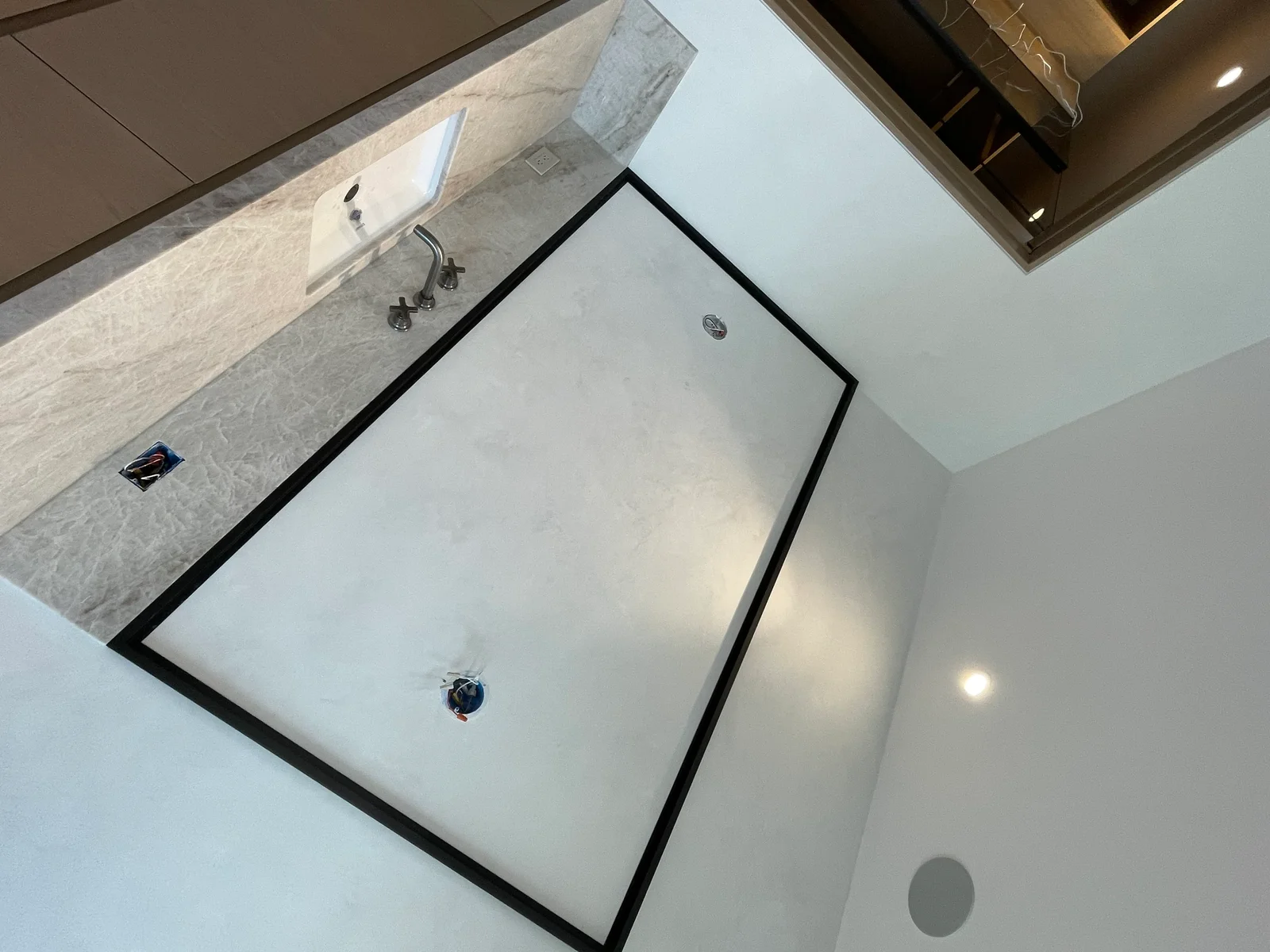 White painted bathroom walls and ceiling with black-framed shower enclosure and marble countertop