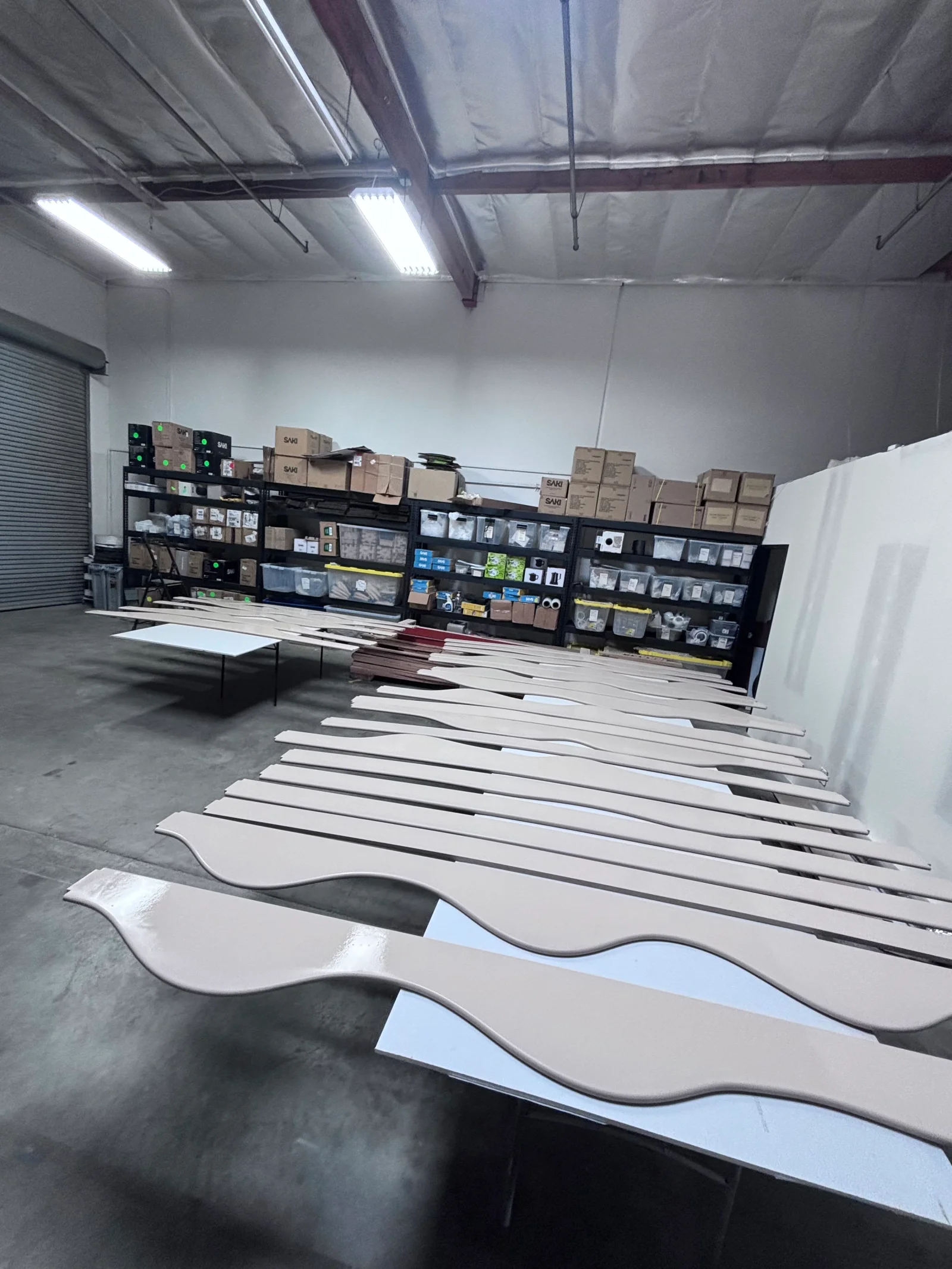 White curved architectural trim pieces with black accent stripes, prepared for finishing in workshop