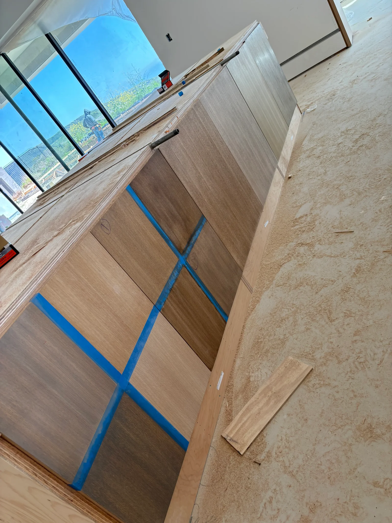 Wood interior doors with blue painter's tape masking, concrete floor, preparation for finishing work