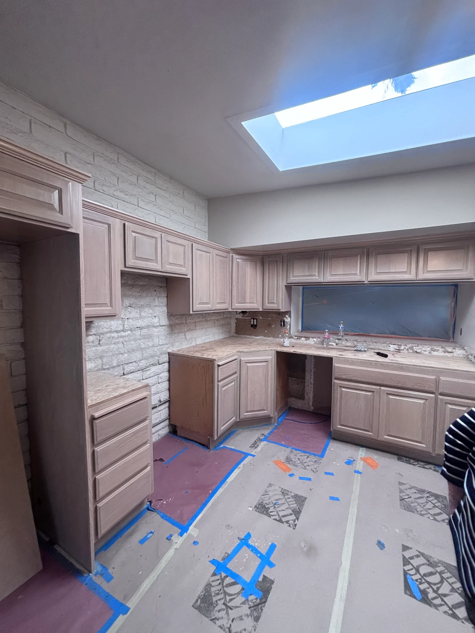 Painted kitchen cabinets in mauve with brick backsplash and skylight, mid-project