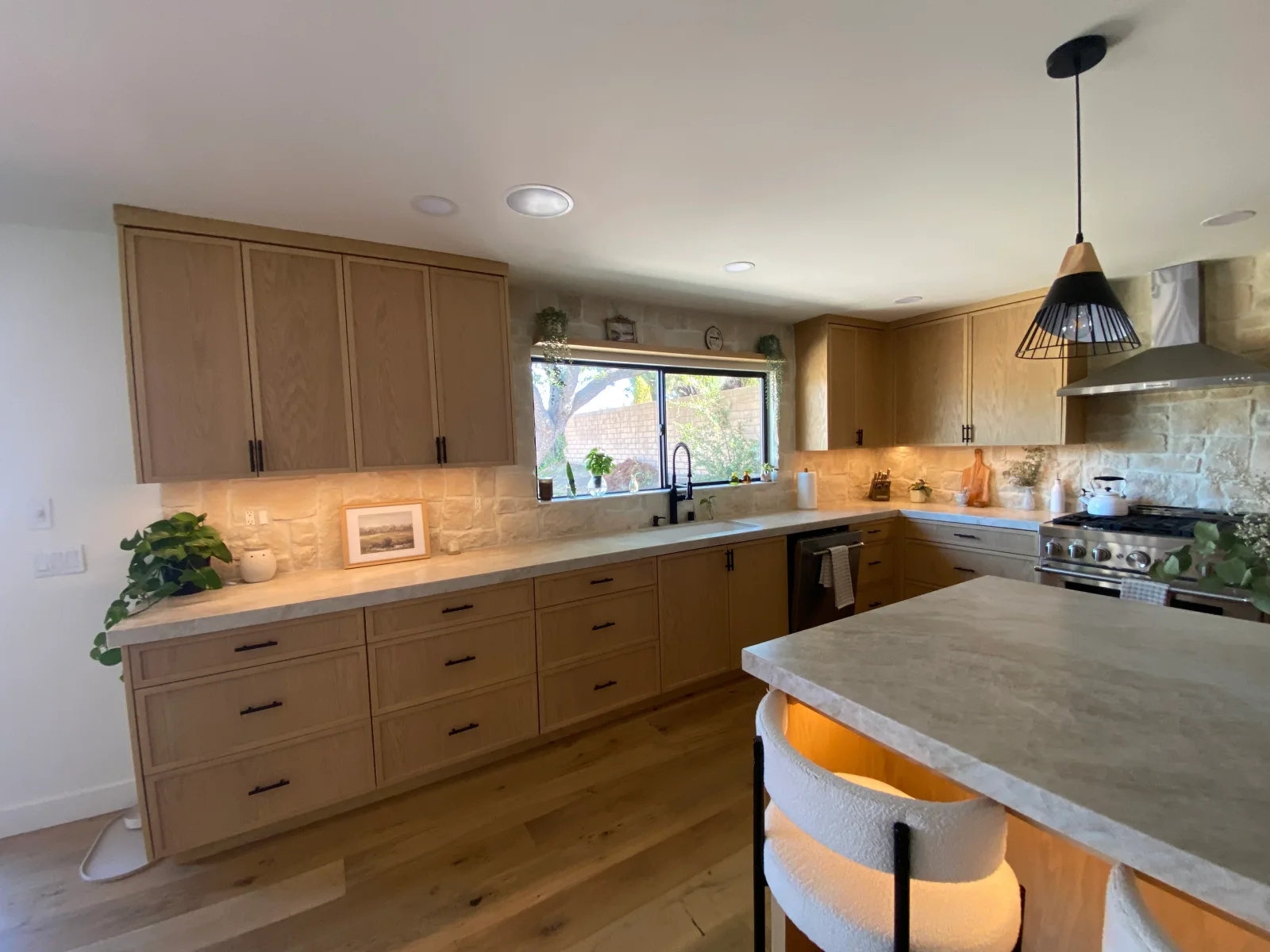 Kitchen with painted wood cabinets, stone countertops, and warm accent lighting
